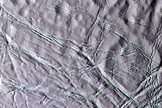 Cassini color image of "snowy" landscape of Enceladus. This terrain lies north of the geologically active south polar ridges and features a rolling terrain crosscut by narrow fractures.