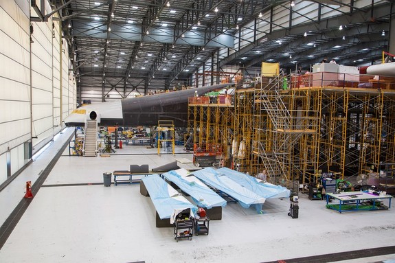 A part of one of the two fuselages of Stratolaunch emerges from the scaffold.